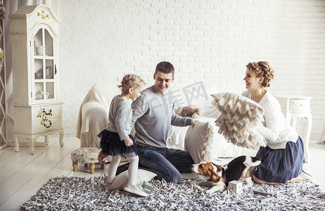 古人枕头摄影照片_幸福的家庭和宠物狗在宽敞的客厅里玩枕头