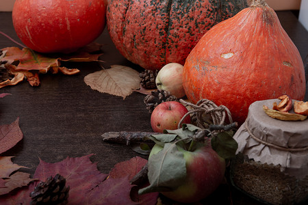 深棕色木桌上的秋意、南瓜、树叶、苹果和干果、复制空间、顶视图