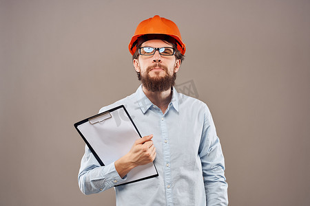 一个身穿橙色油漆的男子，手里拿着文件，正在建设一家工业企业