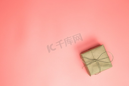 用牛皮纸包裹的礼品盒，粉色背景的粉色礼品盒，带复制空间顶视图，母亲节，情人节，生日概念。