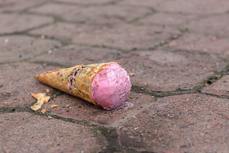 破损感摄影照片_落在人行道上的草莓冰淇淋和破损的华夫饼锥