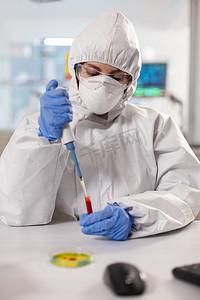 身穿个人防护服的科学家使用微量移液器采集血液样本