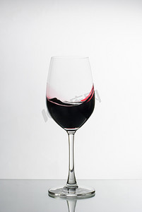 溅起的红酒摄影照片_丰富的深红葡萄酒在酒杯中旋转