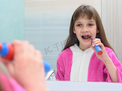 女孩照镜子用电动牙刷刷牙