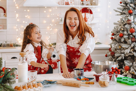 妈妈和女儿在新年厨房里一起准备圣诞饼干的面团