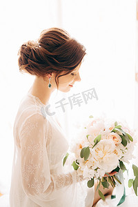 美丽温柔的新娘，带着奶油玫瑰和桉树的新娘花束