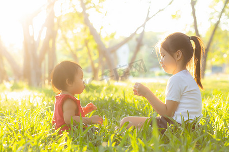 小孩子摄影照片_夏天，漂亮的亚洲小孩子坐在公园里玩耍