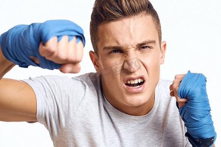戴着蓝色手套的运动男拳击手在浅色背景裁剪视图中练习拳击