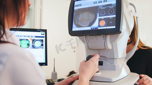眼科诊断摄影照片_高科技医疗保健 — 眼科诊所的眼科医生通过现代计算机技术与患者合作