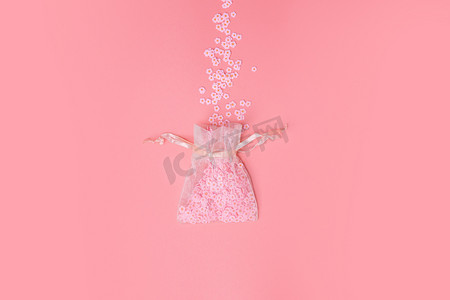 透明纱布摄影照片_粉红色背景纹理的欧根纱袋，美丽的花朵绽放，白色雏菊，春天，母亲节，爱情，假日最小的概念。