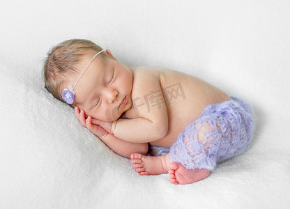 可爱的熟睡新生儿，手放在头下，穿着紫罗兰色内裤