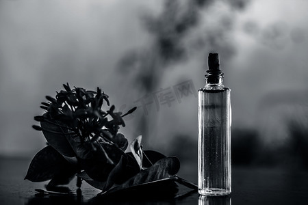 在透明玻璃瓶中用提取的喷雾或香水在木质表面上关闭红色五角花或埃及星花或茉莉花。