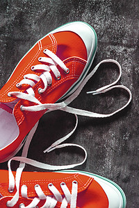 混凝土垃圾深色背景和鞋带心形的红色运动鞋。
