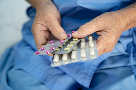 亚洲老年或老年老妇患者拿着泡罩包装的抗生素胶囊药丸，用于治疗医院感染患者；