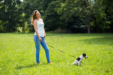 遛狗的女人摄影照片_带着狗杰克罗素梗犬在大自然中散步的女人