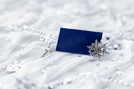 白色假日背景与闪闪发光的银色雪花、圣诞装饰品和空纸为您的文本。