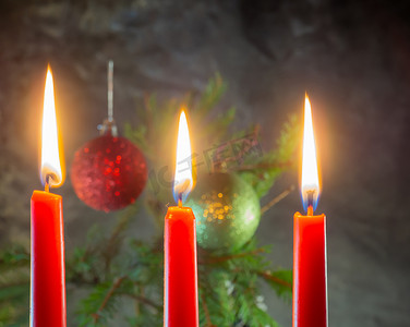 圣诞红蜡烛在冷杉树枝的背景上燃烧。