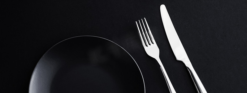 黑色背景高级摄影照片_黑色背景中的空盘子和银器、假日晚餐的高级餐具、简约的设计和饮食