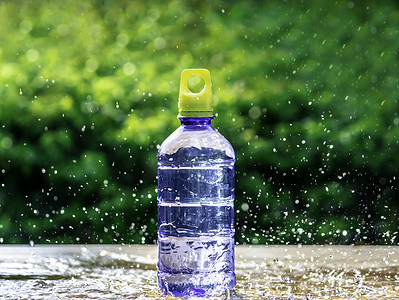 背景模糊的瓶子周围飞溅的新鲜纯净水。
