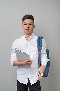 鼠年国潮背景摄影照片_快乐休闲的亚洲男学生使用灰色背景中隔离的平板电脑