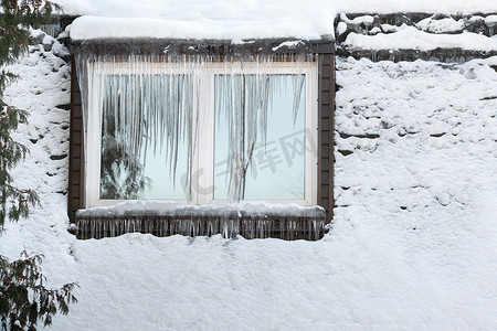 在寒冷的日子里，房子的窗户上结满了冰柱。