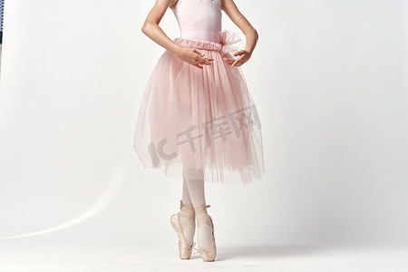 美舞蹈摄影照片_穿着粉红色舞蹈服装芭蕾舞足尖鞋芭蕾舞短裙浅色背景模型的女孩芭蕾舞演员