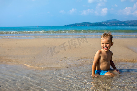 夏天快乐的小孩坐在海边的水中