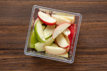 绿色和红色的苹果被切成块，放在透明的 b 中