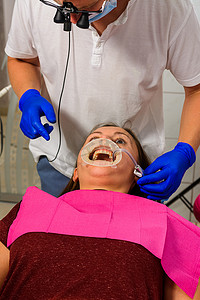 牙医为患者准备通过超声在患者唇部牵开器上去除牙垢的手术。