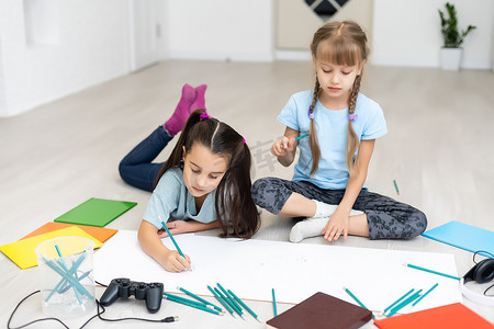 的铅笔摄影照片_可爱的孩子们躺在家里的地板上微笑着画画