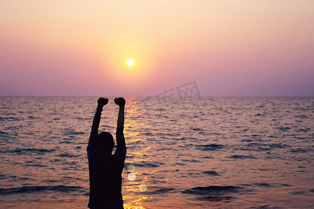 男人举起手来迎接蓝天和夏日海滩背景的天空自由概念。