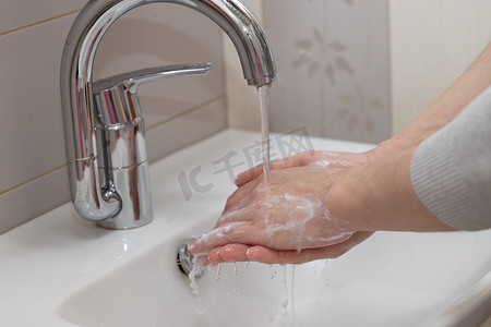鱼儿漏出水面摄影照片_男人用肥皂和泡沫肥皂水洗手。