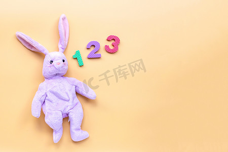 兔子圆摄影照片_带有黄色背景数字的兔子玩具。