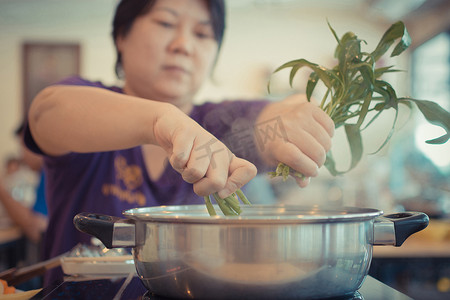 铃木里美摄影照片_亚洲女人把蔬菜放进火锅里做饭