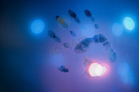 夜间湿玻璃上的手印呈冷蓝色，背景模糊的路灯