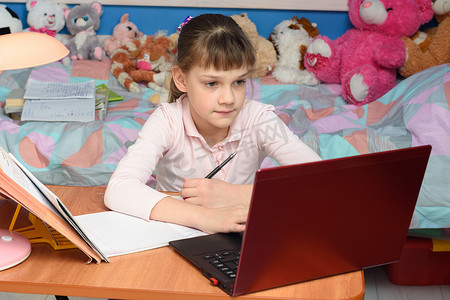 九岁的女孩坐在笔记本电脑前做作业