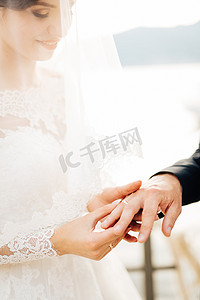 双人结婚登记照摄影照片_婚礼期间，新娘将戒指戴在新郎的手指上