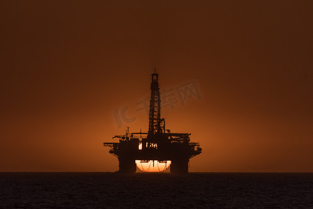 纳米比亚长滩石油钻井平台后面的太阳落山