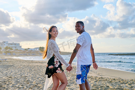幸福的年轻多民族夫妇手牵着手在海边的肖像