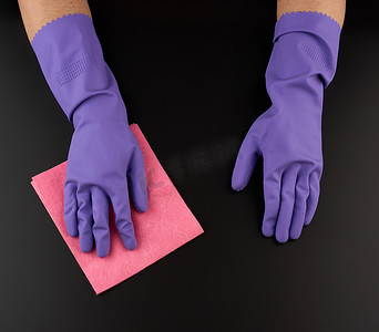 手拿抹布摄影照片_手拿着一块粉色抹布海绵，用于清洁、保护性紫色摩擦