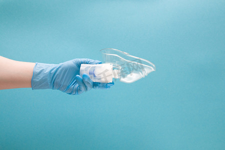 蓝色一次性医用手套中的女手握有带硅胶面罩的雾化器药物储库、吸入装置、肺病学概念、蓝色背景、复制空间