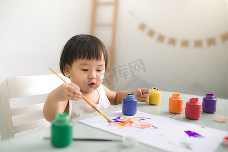 孩子彩色铅笔摄影照片_有趣的笑亚洲女婴在家里用彩色铅笔画画