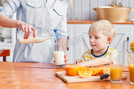 早上喝牛奶摄影照片_这个男孩用玻璃杯喝牛奶。