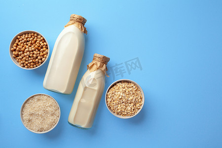 纯粮食摄影照片_两玻璃瓶非乳制纯素牛奶，上面有一碗谷物顶视图