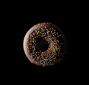 黑色背景上悬浮着彩色巧克力甜甜圈