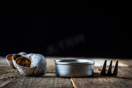 蜗牛壳摄影照片_木制旧桌上的蜗牛壳和锡罐