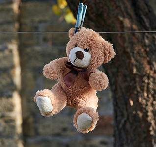 夹娃娃摄影照片_挂在晾衣绳上的旧泰迪熊
