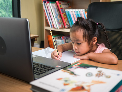 可爱的小女学生在家在线上课时学习数学作业，在冠状病毒爆发期间保持社交距离。