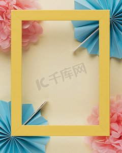 蓝色花瓣边框摄影照片_黄色木质边框框架纸花米色背景。