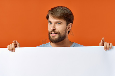 广告海报在一个橙色背景的男人手中，用手做手势复制空间模型